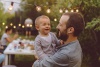 Father holding smiling child at a backyard picnic