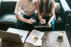 Couple working on paperwork with laptop and tablet.