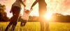 Couple swinging child between them in field.