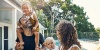 Smiling man in yard of home with woman, young girl, and baby.