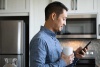 man in kitchen looking at phone