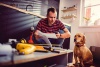man in striped shirt looking at phone with dog