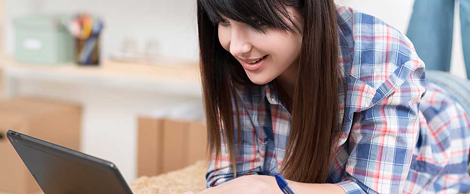 Young girl relaxing on her bed with her laptop